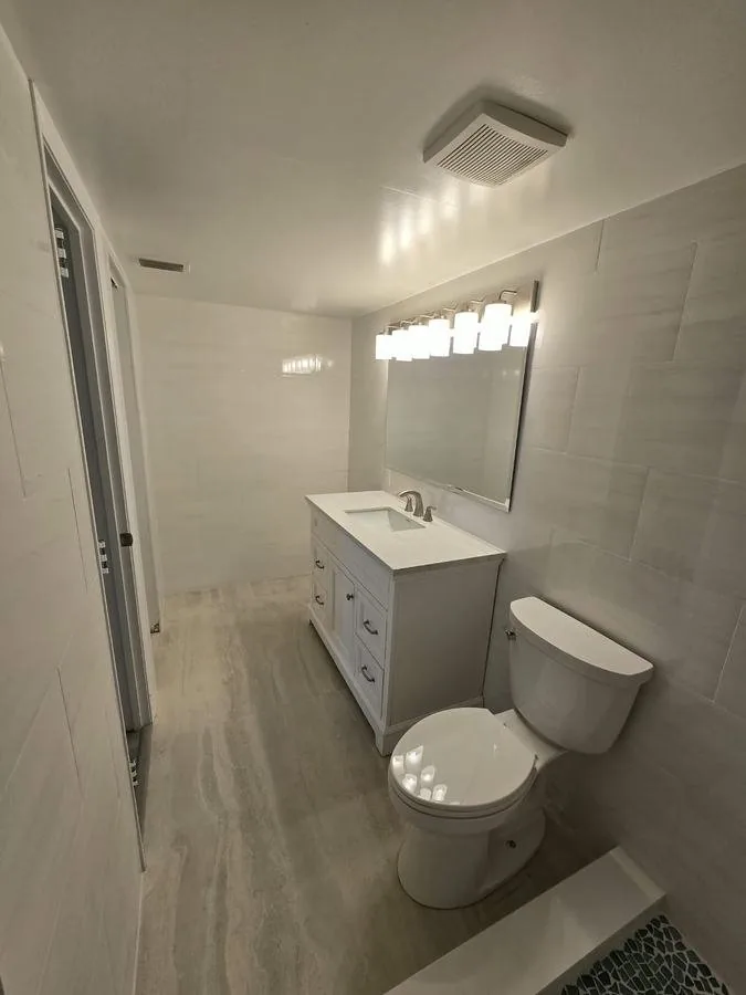 Bathroom finished with porcelain wall tile, a white vanity and new floor tile