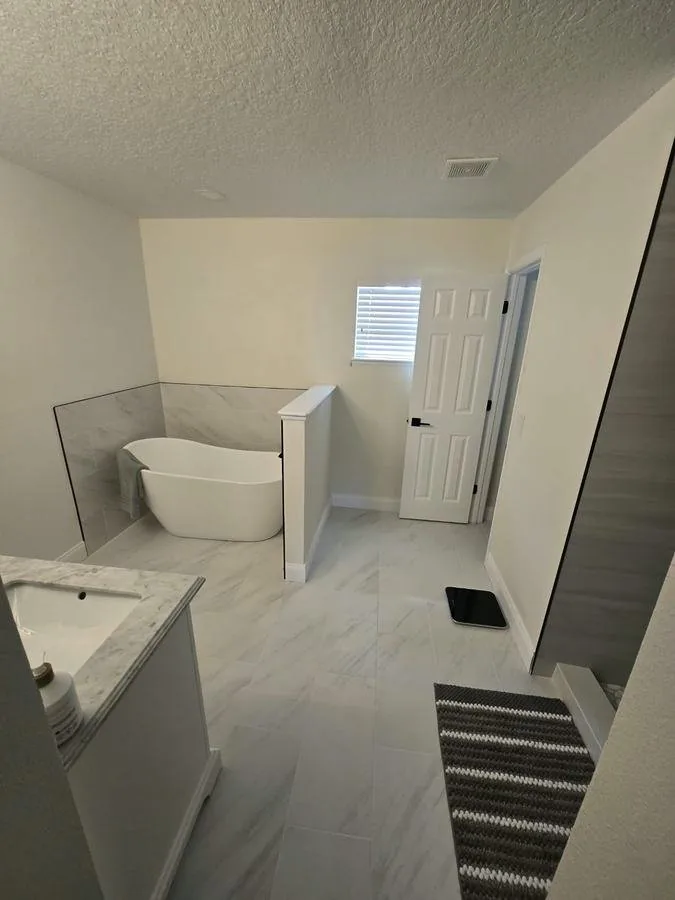 Bathroom floor in large-format marble-look porcelain with a freestanding tub