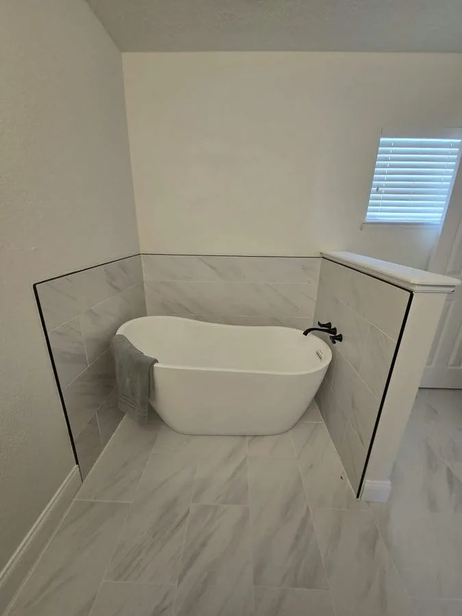 Freestanding tub against a marble-look porcelain wall in a Palm Coast bathroom
