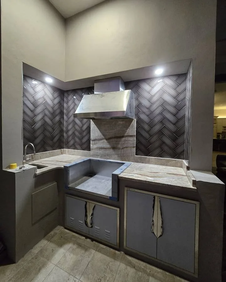 The same corner after the job, in a dark herringbone backsplash behind a stainless range hood