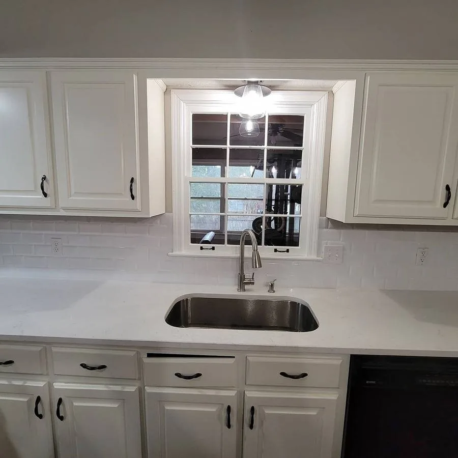The same wall after the job, tiled in white subway backsplash around the window and sink