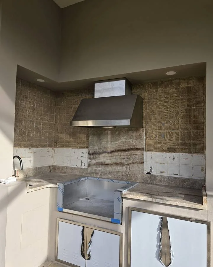 Kitchen corner before the job, with dated stone tile behind the range