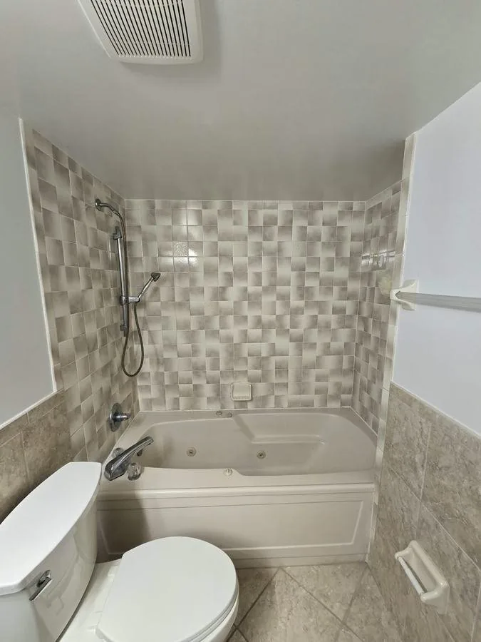 Tub surround retiled in a beige mosaic with the tub and toilet back in place
