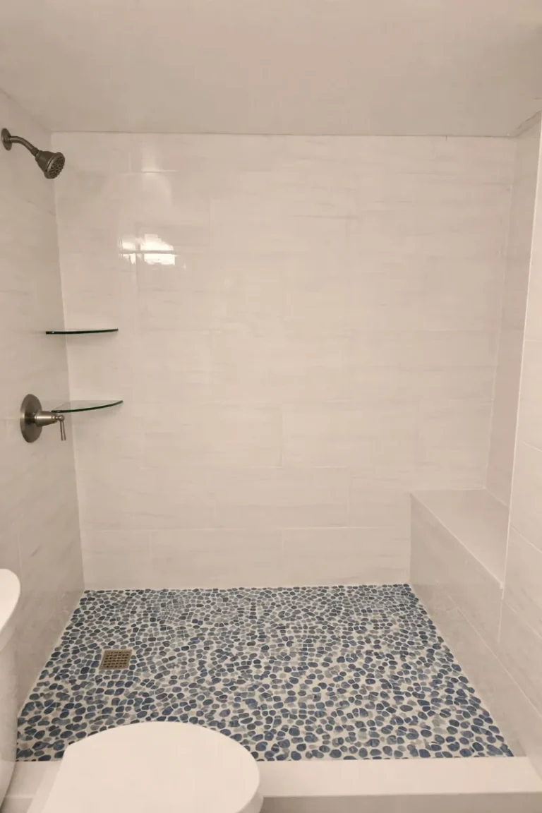 Finished shower with a built-in bench and a pebble mosaic floor replacing the old stall