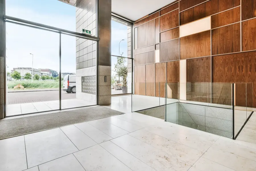Large-format light tile floor in a commercial entrance hall with glass and timber panelling